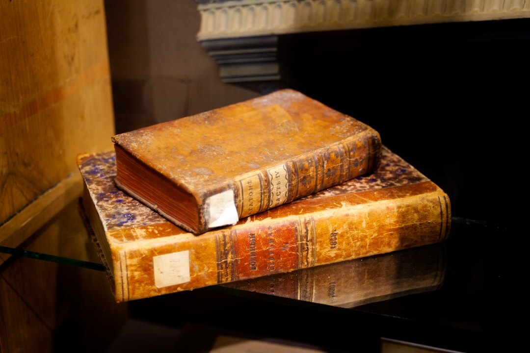 Stack of old leather-bound books with a magnifying glass on top